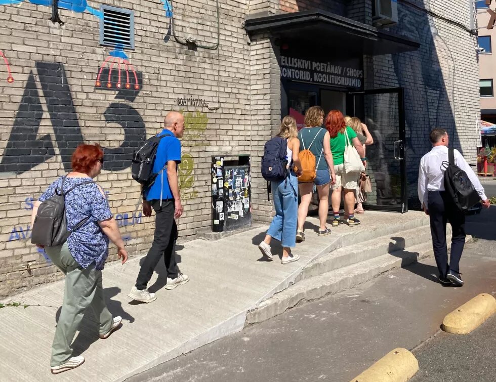 Die Teilnehmenden vom Partnertreffen BSR Cultural Pearls in Tallinn gehen in den Eingang eines Backsteingebäudes, das mit Graffiti besprüht ist.