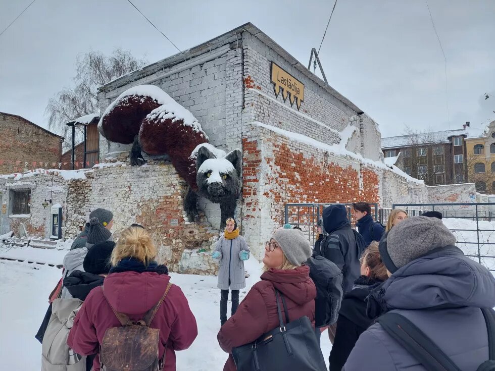 Die CCC-Projektpartner*innen besichtigen Riga. Es liegt viel Schnee. Auf einer Mauer klettert die überdimensionierte Figur eines Fuchses.