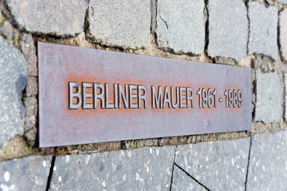 Pflastersteine. In der Mitte befindet sich eine Denkmalplatte mit der Aufschrift "Berliner Mauer 1961 - 1989"